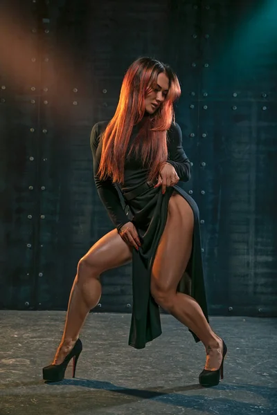 Attraente ragazza dai capelli rossi in abito nero dimostra gambe atletiche — Foto Stock