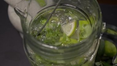 Uzun bir kokteyl kaşığı bir sürahide mojito karıştırır.