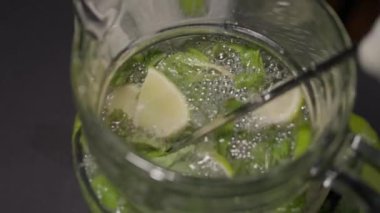 Uzun bir kokteyl kaşığı bir sürahide mojito karıştırır.