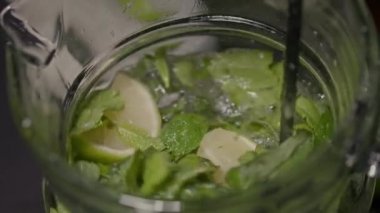 Uzun bir kokteyl kaşığı bir sürahide mojito karıştırır.