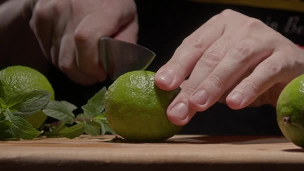 Male hands cut green lime with a knife — Stockvideo
