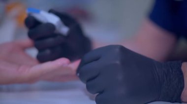 Doktor, modern bir korkuluk kullanarak hastaların yüzük parmağından kan alıyor. Odak kaymaları, yakın çekim.