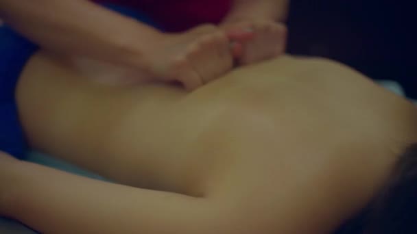 女性のマッサージ師の手は女性の背中をこすり 焦点がシフトします — ストック動画