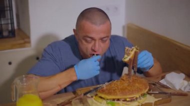 Yetişkin ve kel bir adam terfi için bir süre hamburger yer ve elindeki saate bakar.