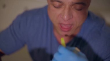 Yetişkin, kel bir adam patates kızartması yer, kameraya bakar ve yırtıcı bir somurtkanlık gösterir.