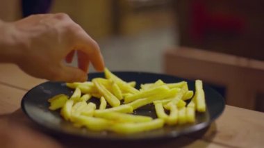 Erkekler siyah şeffaf tabaktan patates kızartması seçer.