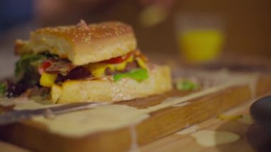 Tahta üzerinde yarısı yenmiş iştah açıcı bir hamburgerin suyu damlıyor.