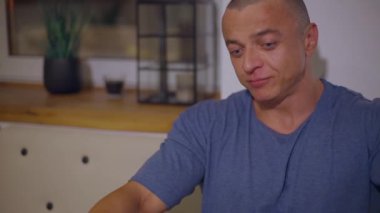 Yetişkin kel adam masada yemek yiyor, bir şeyler söylüyor ve gülüyor.