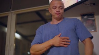 Yetişkin, kel bir adam portakal suyu içiyor ve karnına dokunuyor. Yeterince yediğini gösteriyor.