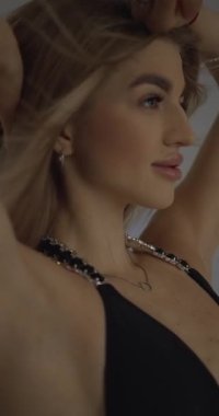 Beyaz arka planda siyah mayo giymiş bir mankenin statik pozu, rüzgar saçlarını geliştirir. Dikey video biçimi, çekim modeli resimleri