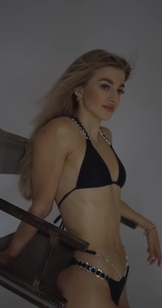 Fitness Modelo Menina Maiô Preto Fundo Branco Posando Inclinado Cadeira — Vídeo de Stock