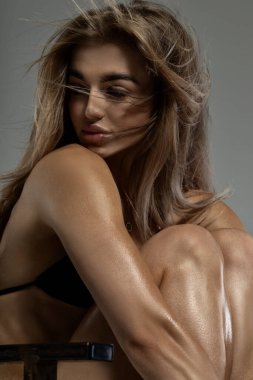 Genç bir kadın modelin portresi. Savunmasız cenin pozisyonu. Güzel, sarı saçlı, mavi gözlü bir kız bir sandalyede otururken dizlerine sarılıyor.