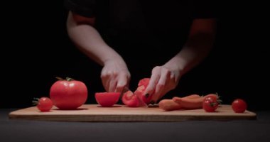 Salata için domates kesen kadın. Dişi eller domatesleri tahta tahtada yavaş çekimde kesiyor. Füzyon yiyecekler, taze sebzeler ve sağlıklı yeme konsepti..