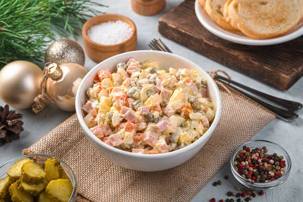 Olivier is a salad of finely chopped vegetables, eggs and sausage on a gray background. — Stock Photo, Image