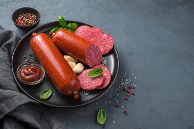 Sarımsaklı sosis, fesleğen ve siyah bir tabakta baharat. Yan görünüm, boşluk kopyala.