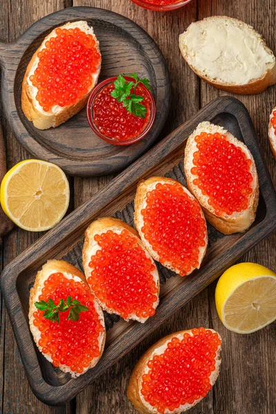 Smörgåsar Med Röd Kaviar Närbild Och Citroner Träbakgrund Ovanifrån Vertikalt — Stockfoto