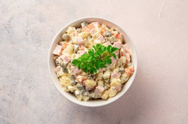 Açık pembe arka planda taze maydanozlu geleneksel olivier. Üst görünüm.