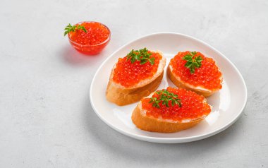 Kırmızı havyarlı sandviçler ve gri arka planda taze otlar. Yan görünüm, boşluk kopyala.