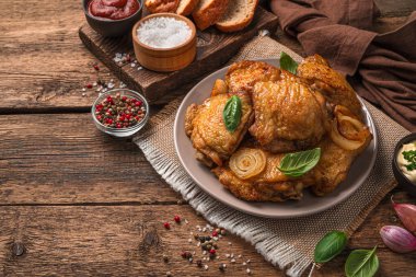 Kızarmış tavuk butları ve ahşap arka planda taze fesleğenli bir tabak. Yan görünüm, boşluk kopyala.