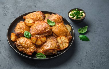 Sulu, kızarmış tavuk butları soğan ve sarımsaklı fesleğen ve sosla kaplanmış koyu bir arka plan..