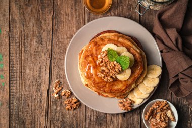 Tahta zemin üzerinde muz, fındık ve bal olan krepler. Üst görünüm, alanı kopyala.