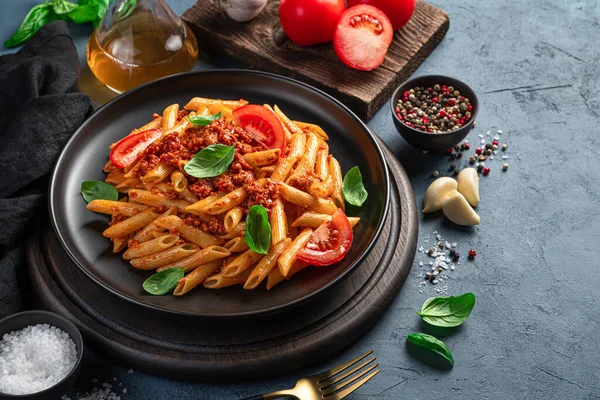 コピーするスペースのある黒鉛の背景にバジルとトマトと伝統的なイタリアのボロネーゼパスタ サイドビュー — ストック写真