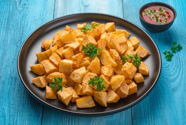 Patatas bravas, mavi arka planda baharatlı domates soslu İspanyol tapas. Yan görünüm, yakın plan.
