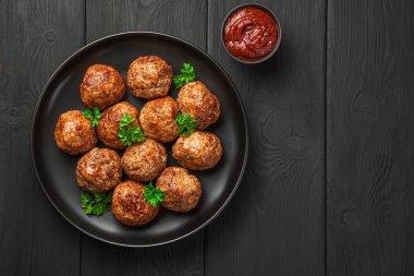 Siyah arka planda fesleğen ve domates soslu köfte. Üst görünüm, alanı kopyala.
