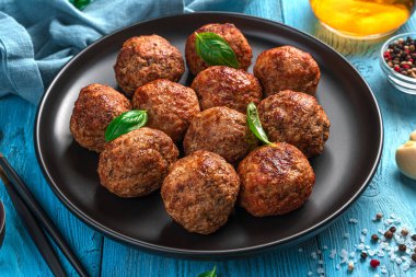 Mavi arka planda fesleğenli kızarmış köfteler. Yan görünüm, yatay.