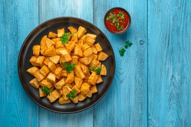 Kızarmış patates, patatas bravas ve mavi arka planda acı sos. Tapas, İspanyol geleneksel atıştırmalığı..