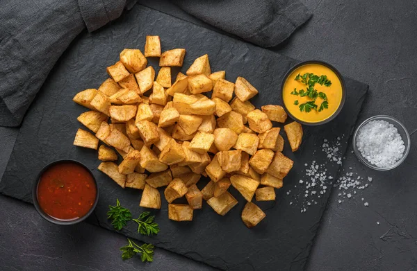 Patatas bravas with sauce on a graphite background with space to copy. Tapas, a traditional Spanish spicy snack.