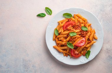 Açık pembe arka planda makarna ve bolonez soslu bir tabak. Geleneksel İtalyan yemeği..