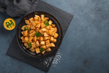 Koyu arkaplanda tuzlu ve soslu kızarmış patates. Patatas bravas, geleneksel İspanyol aperatifi, tapas..