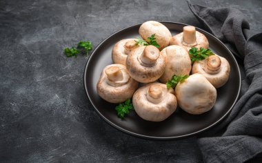 Siyah arka planda bir tabakta çiğ mantar. Yan görüş, kopyalama alanı. Aşçılık şampiyonları.