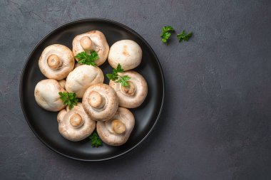 Siyah arka plandaki tabakta taze mantarlar. Üst görünüm, alanı kopyala.