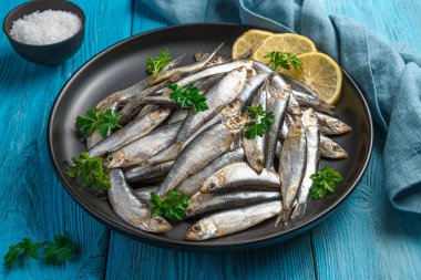 Mavi arka planda bir tabakta limonlu tuzlu sprat. Yan görünüm, yakın plan.