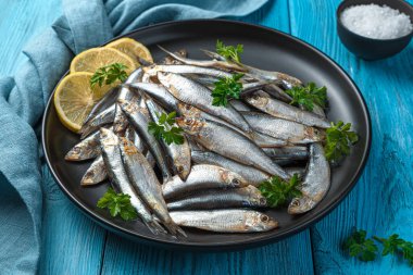 Mavi arka planda limonlu ve maydanozlu tuzlu sprat. Yan görünüm, yakın plan.
