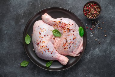 Taze tavuk butları tabakta baharatlarla pişirilmeye hazır..