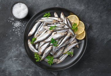 Limonlu, tuzlu ve maydanozlu sardalyalar koyu bir arka planda..