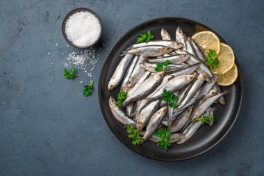 Limonlu sardalya, tuz ve koyu mavi arka planda taze otlar. Üst görünüm, alanı kopyala.