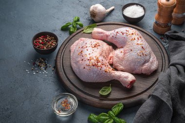 Grafit arka planda baharat ve tuzla ovulmuş tavuk bacakları. Yemek pişirmek. Yan görünüm, boşluk kopyala.