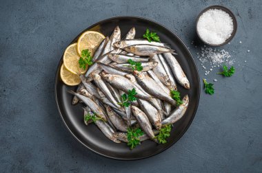 Koyu arkaplanda limonlu ve maydanozlu sardalya. Üst görünüm, yakın çekim.