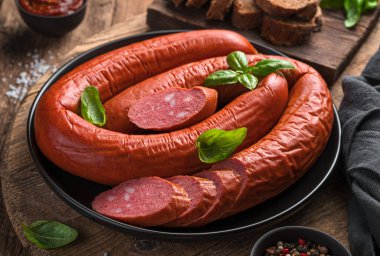 Tahta arka planda taze fesleğen, baharat ve sarımsaklı Krakow Sosisi. Yakın plan..