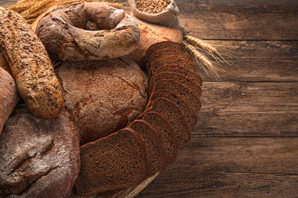 Ahşap arka planda çavdar ve buğday ekmeği çeşitleri. Yan görünüm, boşluk kopyala.