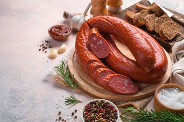 Tütsülenmiş, arka planda ekmek, sarımsak ve baharatlarla birlikte bir kesim tahtasının üzerinde Krakov sosisi. Yan görünüm, boşluk kopyala.