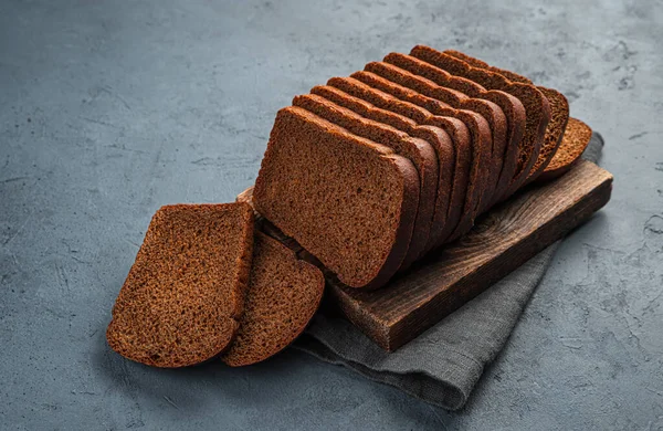 Çavdar ekmeği grafit arkaplanda parçalara ayrılmış. Yan görünüm, yatay.