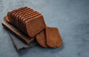 Bir somun çavdar ekmeği grafit arka planda parçalara ayrılmış. Yan görünüm, boşluk kopyala.