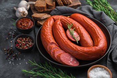 Siyah arka planda taze biberiye ve baharatla tütsülenmiş sosis. Yan görünüm, boşluk kopyala.