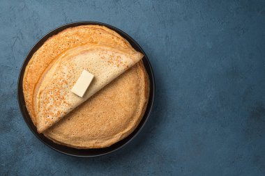 Gri-mavi arka planda tereyağlı geleneksel kızarmış krep. Maslenitsa. Üst görünüm, alanı kopyala.