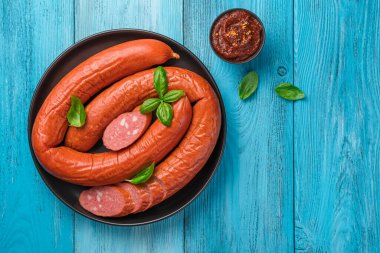 Fesleğen ve soslu füme sosis, mavi arka planda. Üst görünüm, alanı kopyala.